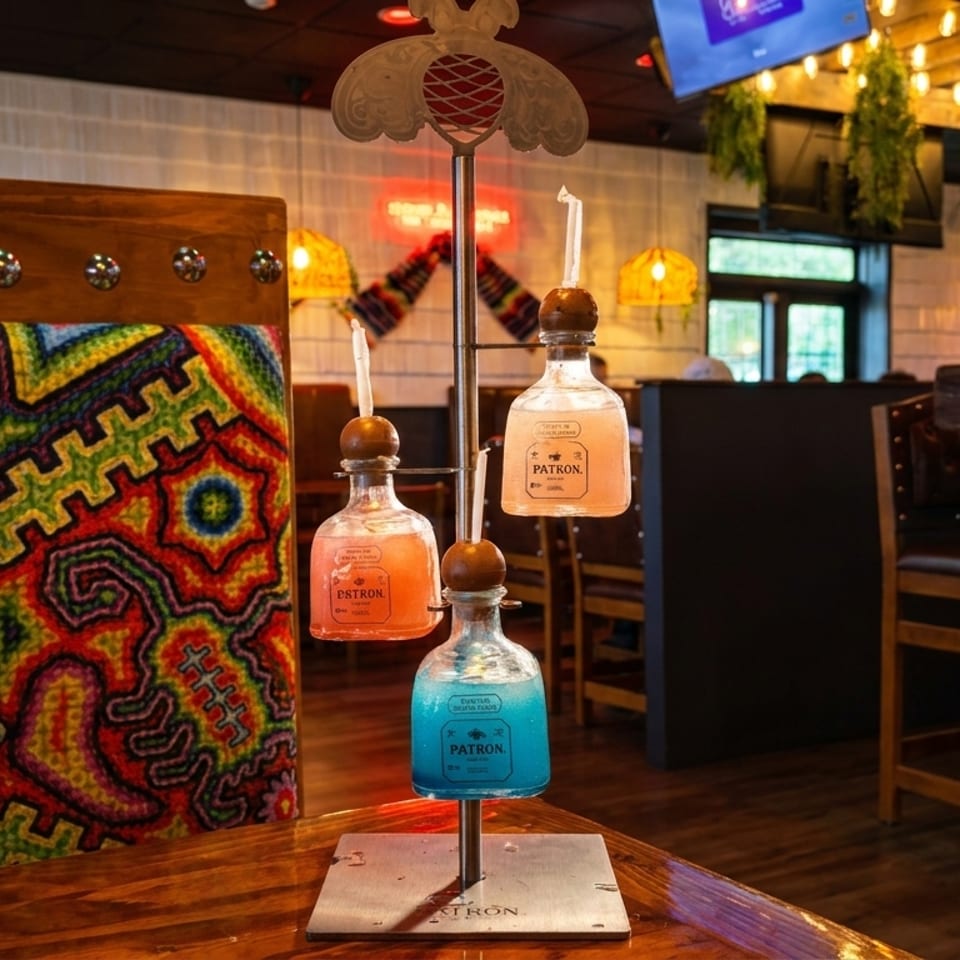 Colorful Patron margarita flight on a wooden table with a vibrant patterned wall and restaurant interior.