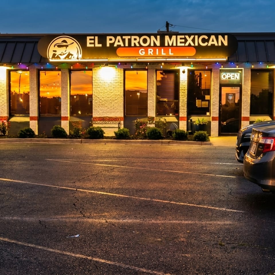 El Patron Mexican Grill exterior at dusk, with illuminated windows, colorful lights, and cars in the parking lot.